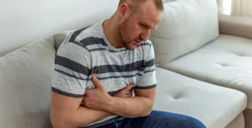 Man experiencing abdominal pain and digestive discomfort, a common symptom of autoimmune gastritis