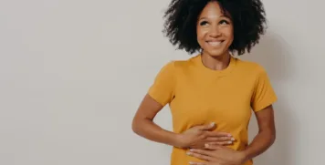 Smiling woman touching stomach after digestive relief and gut health treatment
