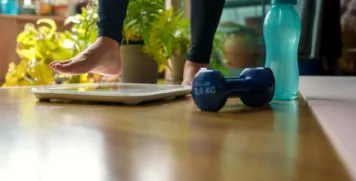 Barefoot person measuring weight on scale during a home workout session